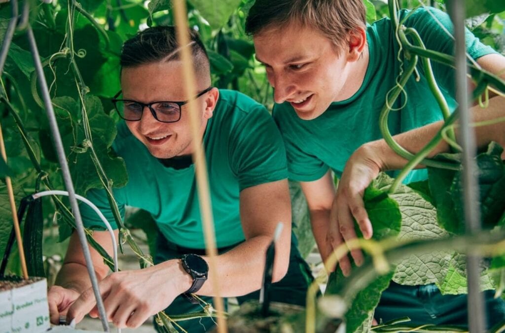 Dva muži jsou sehnutí k rostlině a kontrolují senzory, které jsou napojené na její kořeny